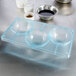 A clear plastic tray with three half sphere bowls on a metal surface.