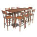 A Lancaster Table & Seating solid wood live edge bar table with chairs around it.
