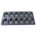 A black baking tray with 12 shell-shaped molds.