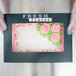 A person holding a 14" x 10" x 4" bakery box with frosting flowers