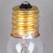 A close-up of a Satco clear incandescent indicator light bulb with a gold base.