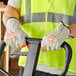 A person wearing Cordova warehouse gloves with hi-vis orange fingertips holding a forklift handle.