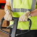 A man wearing Cordova pigskin leather gloves and a yellow safety vest holding a forklift.