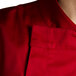 A close up of a tomato red Chef Revival chef jacket with hidden snap buttons.