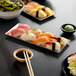 A rectangular stainless steel tray with sushi and chopsticks.