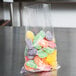 A LK Packaging plastic food bag filled with colorful candies on a table.