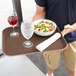 A man holding a Thunder Group rectangular non-skid serving tray with a glass of wine and a bowl of salad.