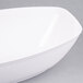 A Fineline white plastic oval bowl on a gray surface.