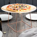 An Acopa rose gold metal display stand holding a pizza on a plate.