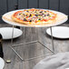 An Acopa stainless steel display stand holding a pizza on a table.