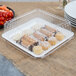 A Fineline white plastic square catering tray with doughnuts and fruit on it.