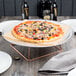 An Acopa rose gold metal display stand with a pizza on a plate.