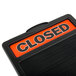 A close up of a Headline Sign "Closed" sign on a black and orange sign.