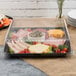 A black Fineline plastic square catering tray with meat, cheese and vegetables on a table.