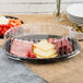 A Fineline black plastic cater tray with meat, cheese, and tomatoes on a table.