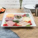 A Fineline white plastic square catering tray with meat, cheese, and vegetables on it.