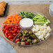 A Fineline clear plastic 7-compartment tray with vegetables and dip.