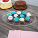 A clear plastic oval platter with cupcakes and cake on a table.