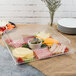 A clear plastic Fineline cater tray with food on a table.