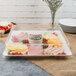 A Fineline white plastic square catering tray on a table with meat, cheese, and vegetables.