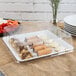 A Fineline white plastic square catering tray with food on it.