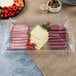 A Fineline clear plastic rectangular catering tray with meat, cheese, and vegetables.