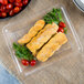 A Fineline clear plastic rectangular catering tray with chicken sticks, bread sticks, and cherry tomatoes.