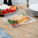 A Fineline clear plastic rectangular cater tray with food in it.