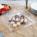 A clear plastic square catering tray with food on it.