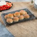 A clear plastic rectangular dome lid on a tray of rolls and vegetables.