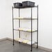A 360 Office Furniture black metal wire shelving unit with black bins and papers on it.