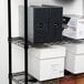 A black wire shelving unit with file folders and boxes on the shelves.