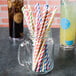 A glass jar filled with Creative Converting striped paper straws.