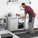 A man in a chef uniform using an Avantco undercounter freezer in a professional kitchen.