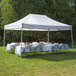A white Caravan Canopy tent set up with tables and chairs on grass.
