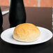 A Carlisle white melamine bread and butter plate with a small bun on it.