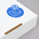 The white Lavex cardboard recycling container lid with a blue and white recycle symbol on it.