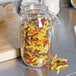 A Choice glass storage jar filled with pasta on a counter.