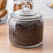 A Choice 0.75 gallon glass jar filled with coffee beans with a lid.