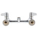 A chrome Equip by T&S wall mounted faucet base with lever handles and supply elbows.