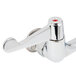 A close-up of a chrome plated Equip by T&S wall mount faucet with white wrist handles.