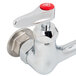 A T&S chrome wall mount faucet with lever handles and a red button.