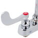 A chrome T&S deck-mounted faucet with red wrist handles.