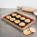 A Sasa Demarle half size silicone baking mat on a baking tray with cookies and a rolling pin.