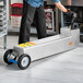 A man uses a Shortening Shuttle to move a metal box on wheels.