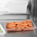 A Rubbermaid clear polycarbonate food storage container on a counter filled with carrots.