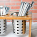 A metal container with spoons and forks in a Cal-Mil perforated stainless steel flatware cylinder.