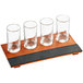 An Acopa Write-On flight tray with four straight up tasting glasses on a table.