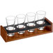 Acopa Write-On Drop-In Flight Carrier with Flared Pilsner Tasting Glasses holding four glasses on a wooden stand.