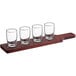 An Acopa mahogany finish wooden tray with four pub tasting glasses in it.
